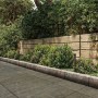 Philips Kyna Solar-Sockelleuchte, schwarz, im Garten zwischen Pflanzen und Holzzaun.
