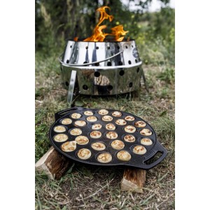 Petromax Poffertjes Pfanne aus Gusseisen mit fertigen Mini-Pfannkuchen und Atago Grill im Hintergrund.