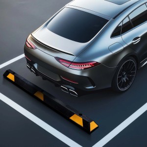 Robuster Gummi Radstopper mit gelben Reflexstreifen als Einparkhilfe vor einem Auto auf einem Parkplatz. Autozubehör.