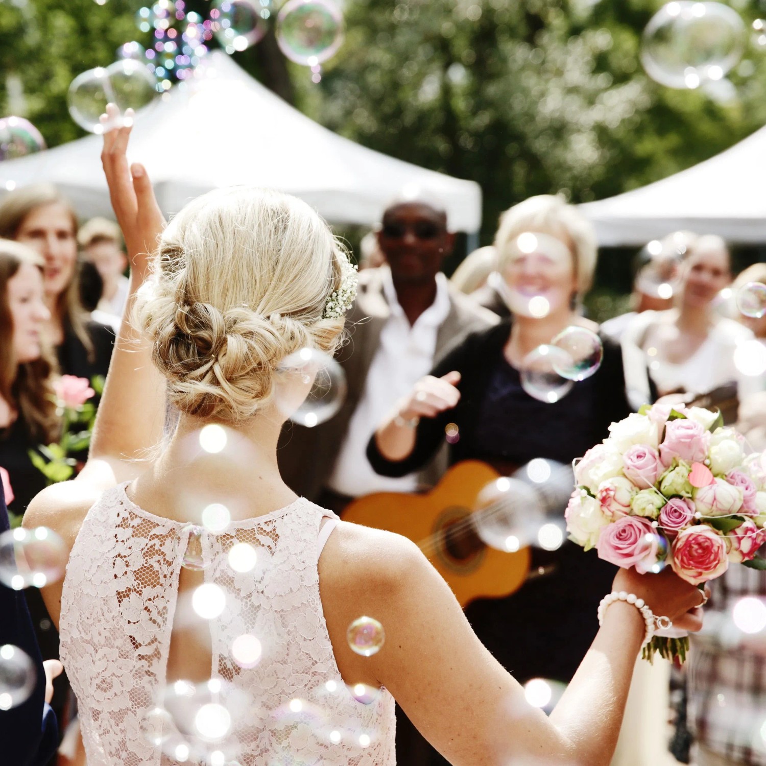 Braut auf Hochzeit, umgeben von Seifenblasen. Festliche Stimmung mit Seifenblasenröhrchen.