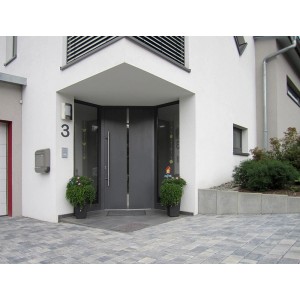 Graue Diephaus L-Steine als Einfassung eines Hauseingangs mit grauer Tür und Pflastersteinen.