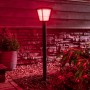 Philips Hue Econic LED-Wegeleuchte in Schwarz, leuchtet rot im Garten.