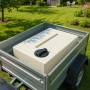 Heller rechteckiger KMND 80L Trinkwasser Wassertank mit schwarzem Deckel im Anhänger im Garten. Für Regentonnen.