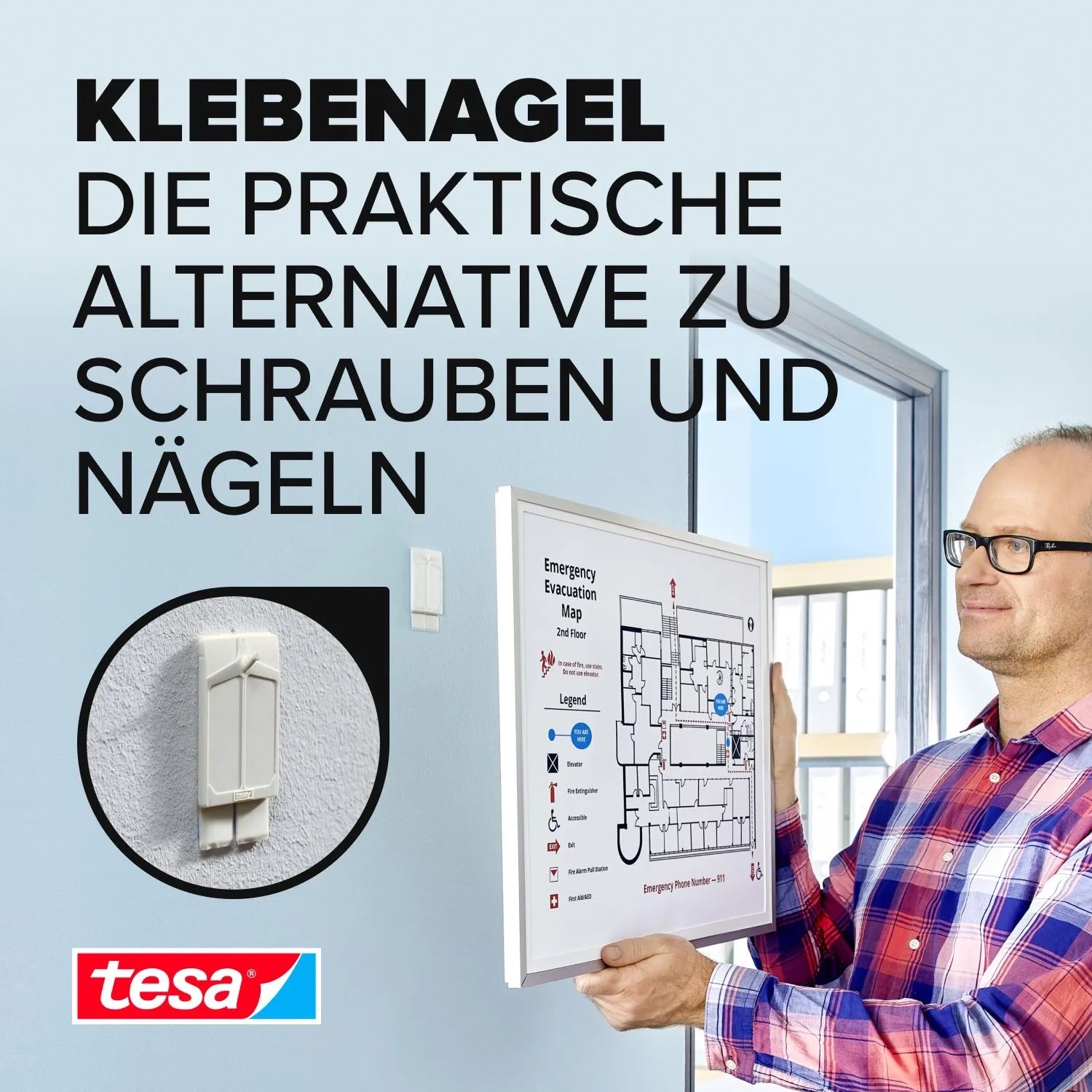 Mann hängt Evakuierungsplan mit Tesa Klebenagel an Wand. Weiße Klebenägel für Tapeten und Putz, halten bis 2 kg.