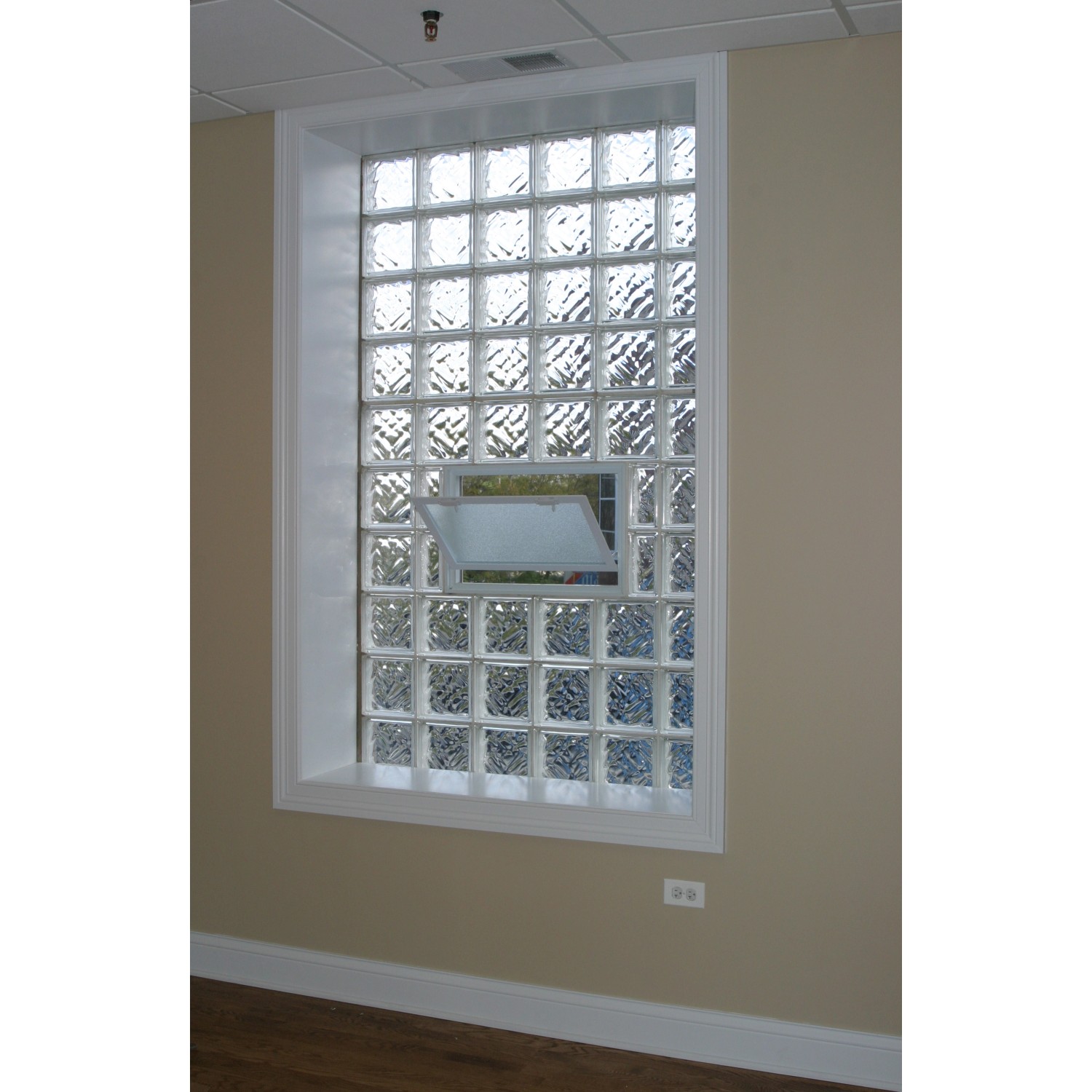 Lüftungsfenster mit Fliegengitter, eingesetzt anstelle von Glasbausteinen in einer Wand.