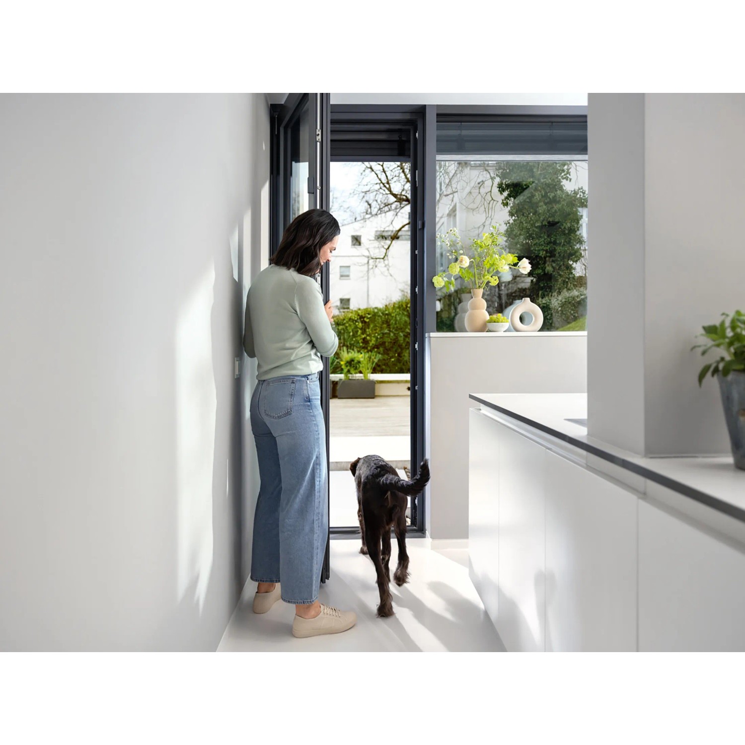 Frau bedient Bosch Smart Home Fenster-/Türsensor II Plus Anthrazit an Terrassentür.