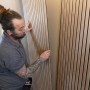Anwender montiert Holzpaneele mit Soudal High Tack Kraftkleber an der Wand.