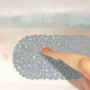Graue Badewanneneinlage in Steinoptik aus PVC mit Saugnäpfen im weißen Bad. Ein Fuß steht auf der rutschfesten Matte.