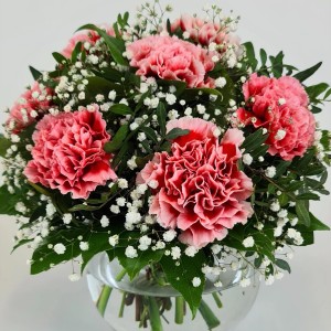 Blumenstrauß Schwärmerei mit rosa Nelken und Rosen in Glasvase, dekoriert mit Schleierkraut.