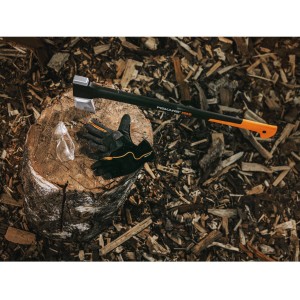 Fiskars Gartenhandschuhe M, Axt und Schutzbrille auf Holzscheit, umgeben von Holzhackschnitzeln.