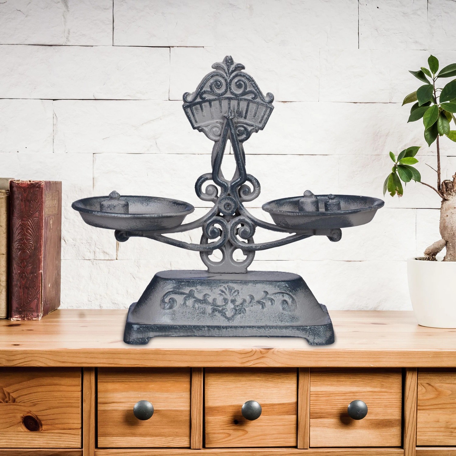 Graue Gusseisen Deko Waage im Antik-Design mit floralen Verzierungen und zwei Schalen auf einer Holzkommode.
