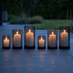 6er Set Windlichter aus Rauchglas mit schwarzen Eisenfüßen in 3 Größen, brennende Kerzen auf dunklem Boden.
