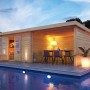 Karibu Holz-Gartenhaus Ängelholm mit Pultdach, unbehandelt, neben Pool mit Sitzbereich.