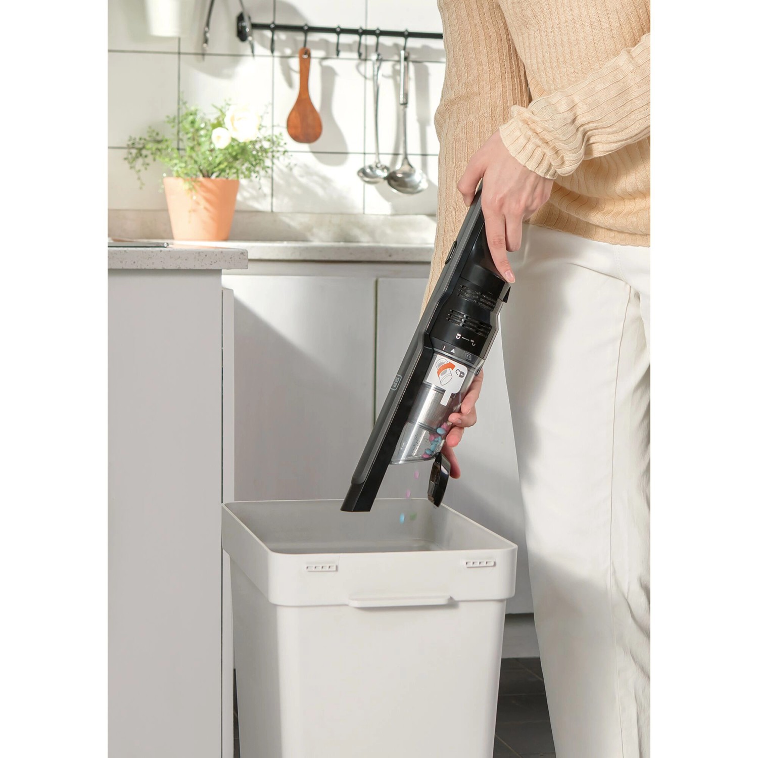 Frau leert Black+Decker Akku-Handstaubsauger Dustbuster Slim in Mülleimer.