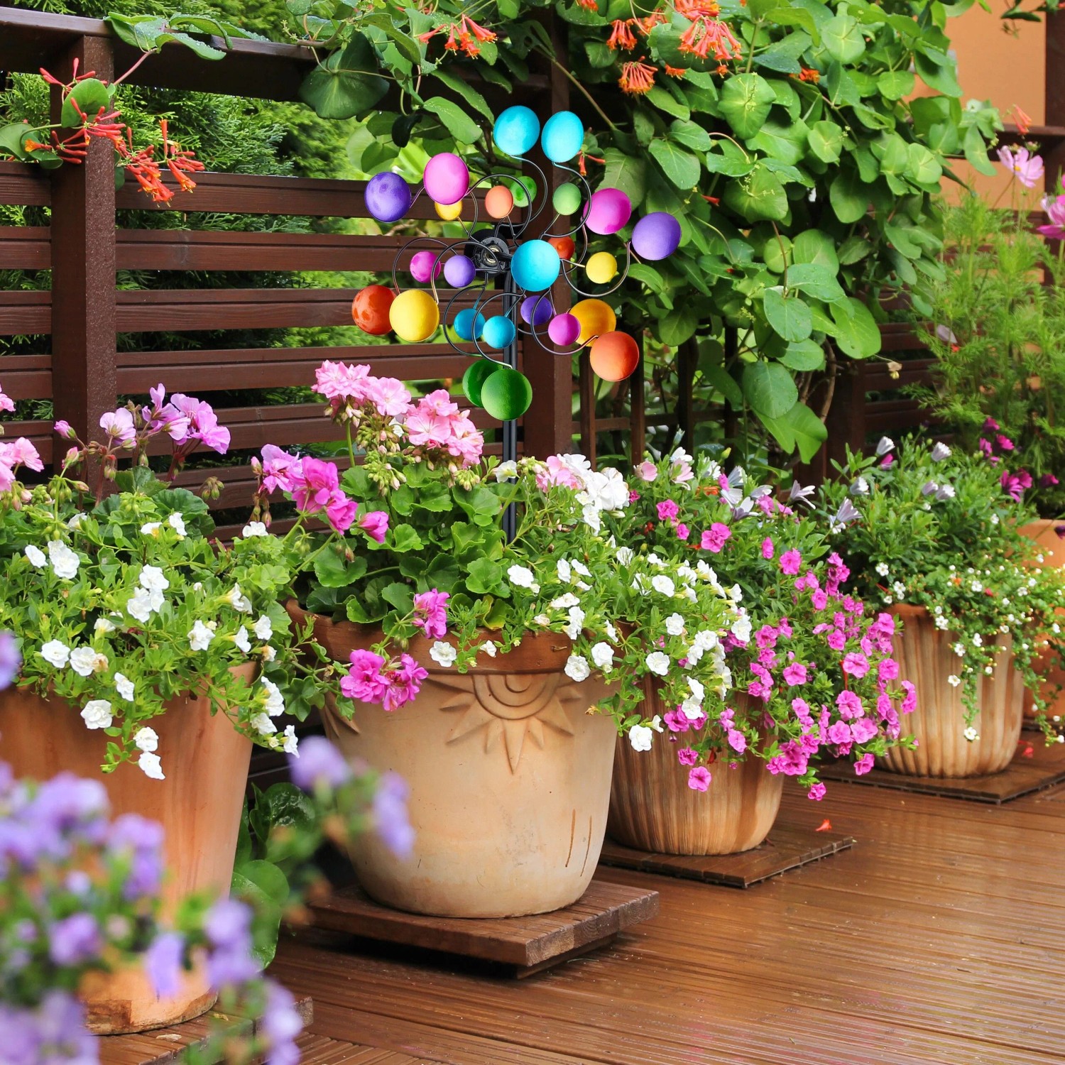 Buntes Relaxdays Windrad aus Eisen mit zwei Rädern und Erdspieß, in Blumenbeet auf Terrasse. Dekorative Gartenfigur.