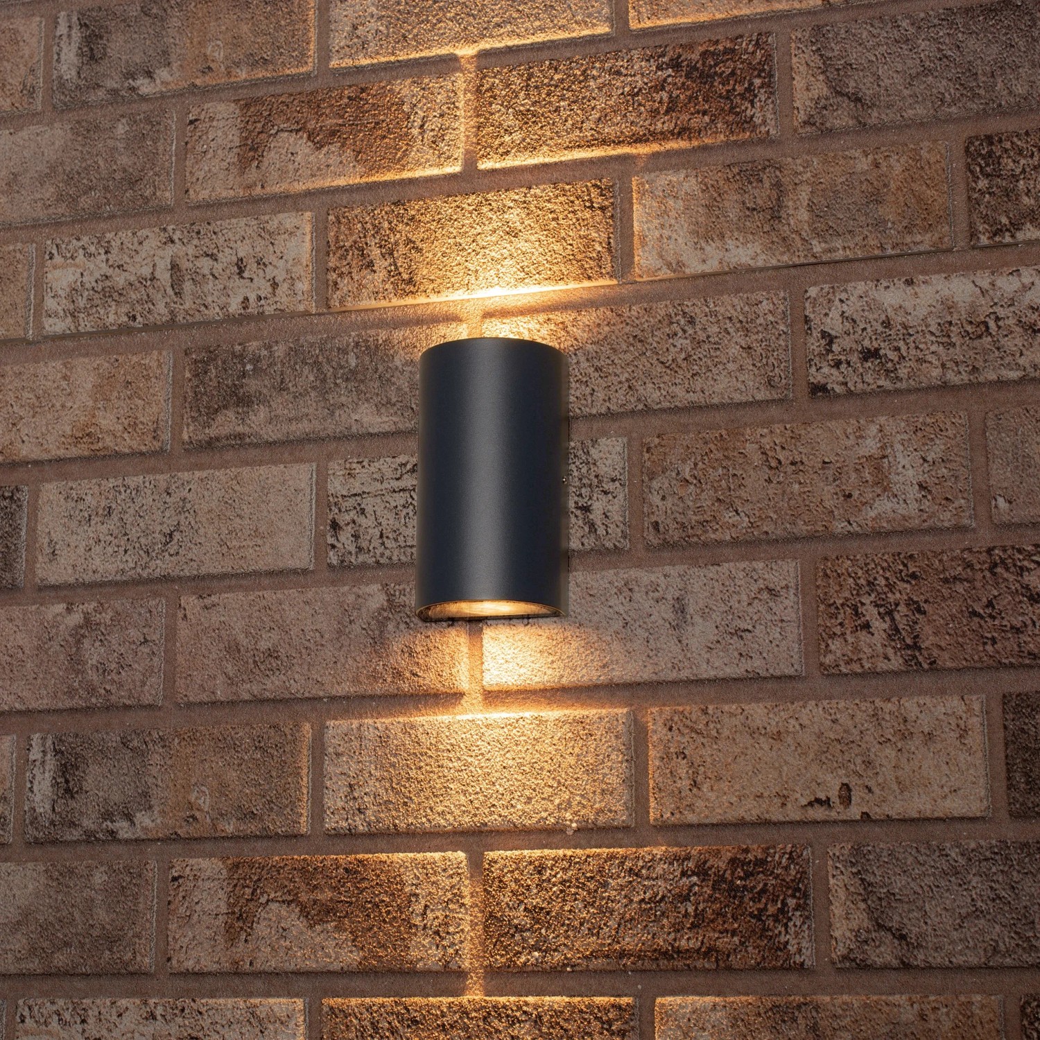Schwarze, halbrunde LED`s light Außenwandleuchte (2-flammig) an einer Backsteinwand.