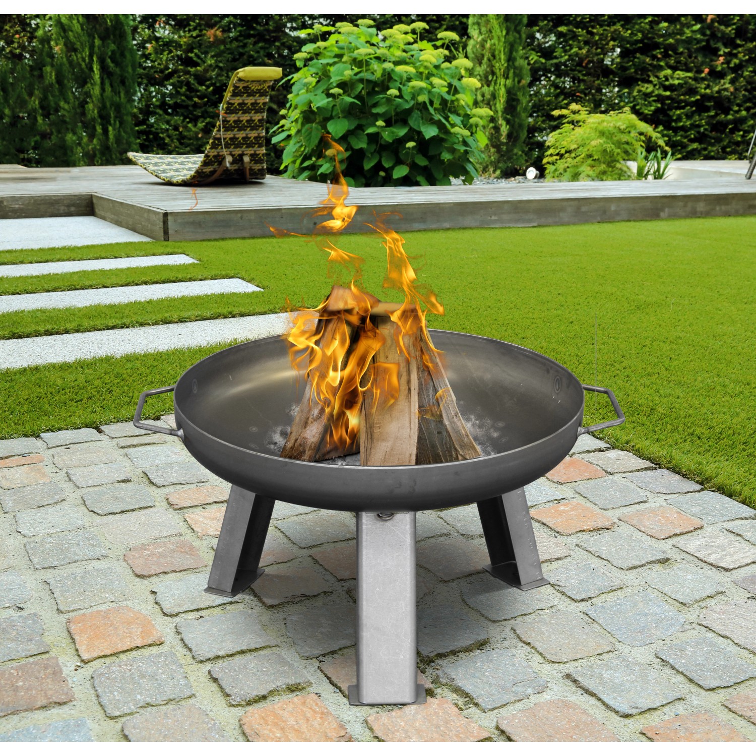 Buschbeck Feuerschale XS (Ø 55cm) aus Eisen mit brennendem Holz im Garten.