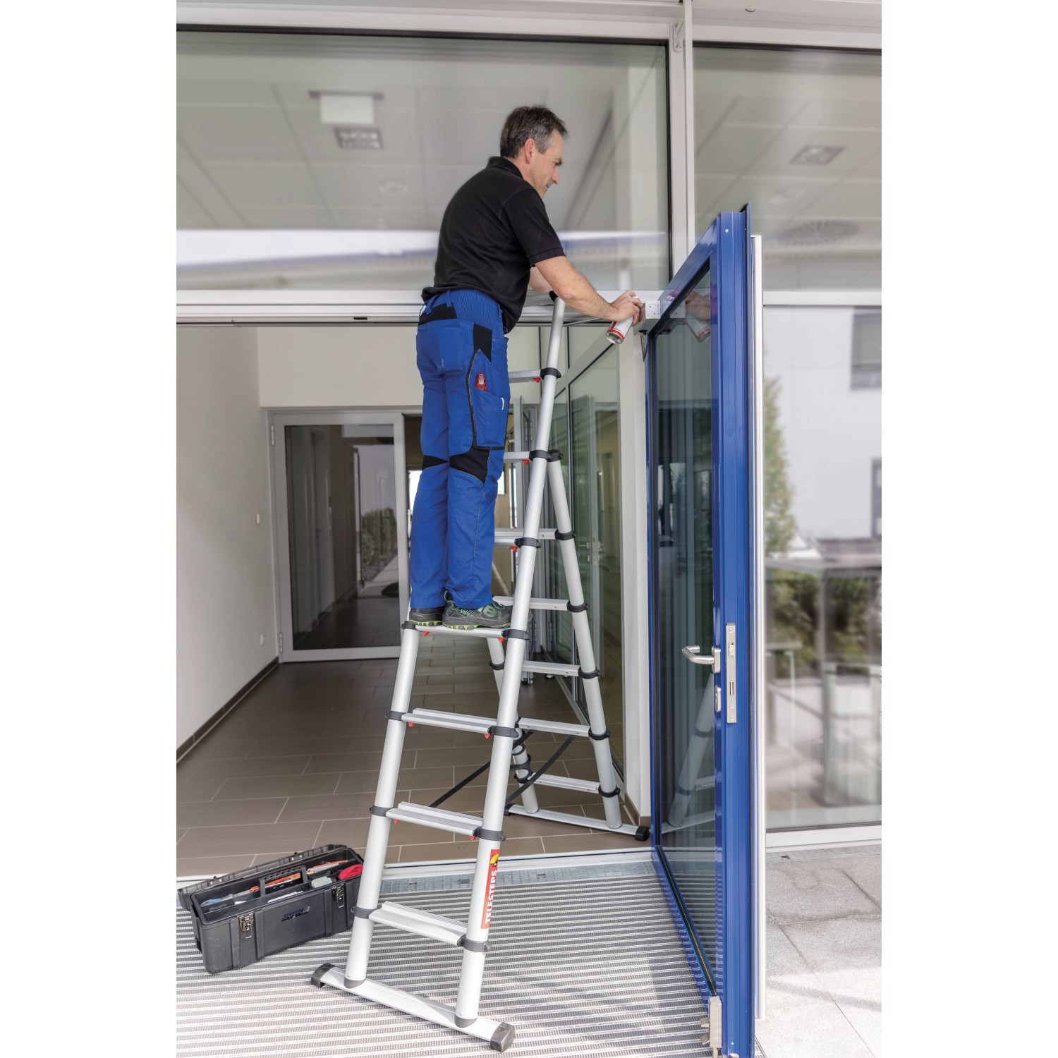 PROREGAL Teleskop-Kombileiter mit Mann bei Reinigungsarbeiten an Fenster.