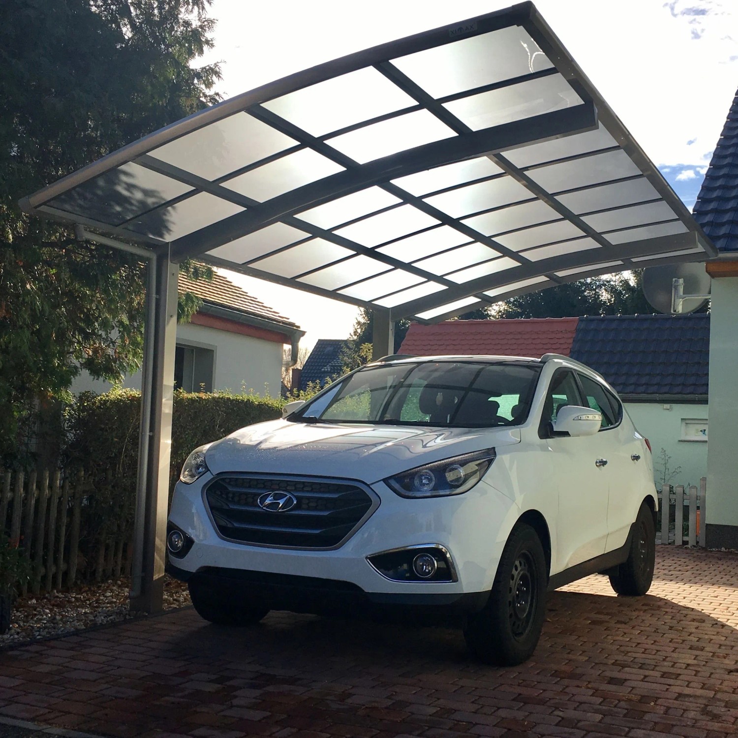 Ximax Carport Portoforte-80 im Edelstahl-Look mit Auto. Moderner Metallcarport mit gebogenem Dach.