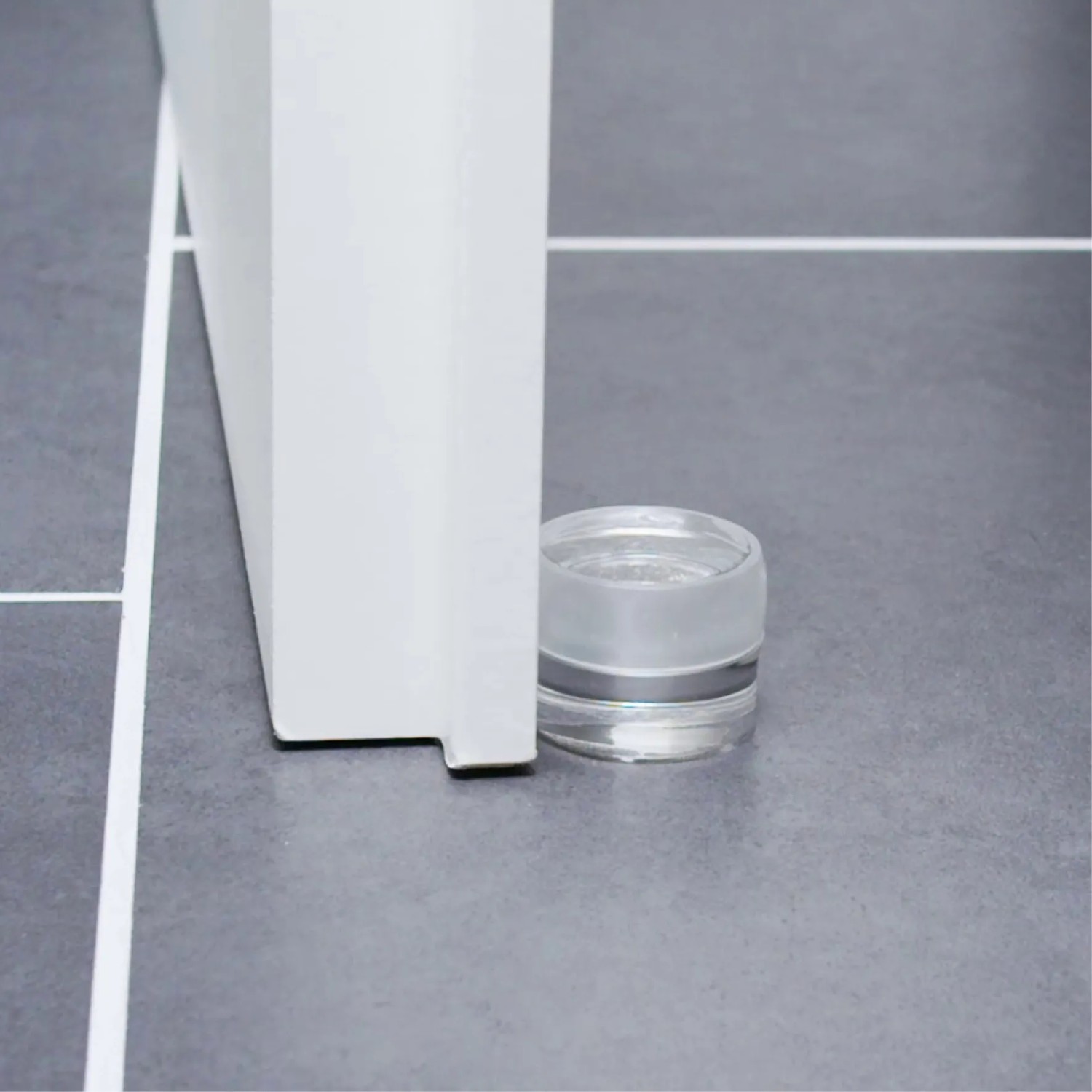 Transparenter Wagner Bodentürstopper Clear (Ø 40 mm) aus Kunststoff auf grauem Fliesenboden.