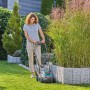 Frau mäht Rasen mit Gardena Akku-Rasenmäher PowerMax 32/18V im Garten.