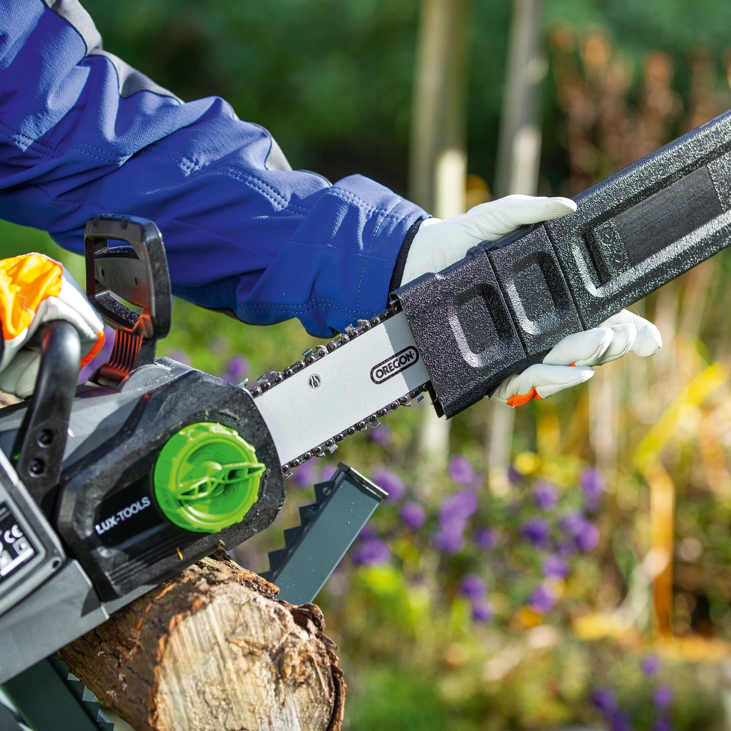 LUX Akku-Kettensäge 1 PowerSystem beim Schneiden von Holz mit Schwertschutz.