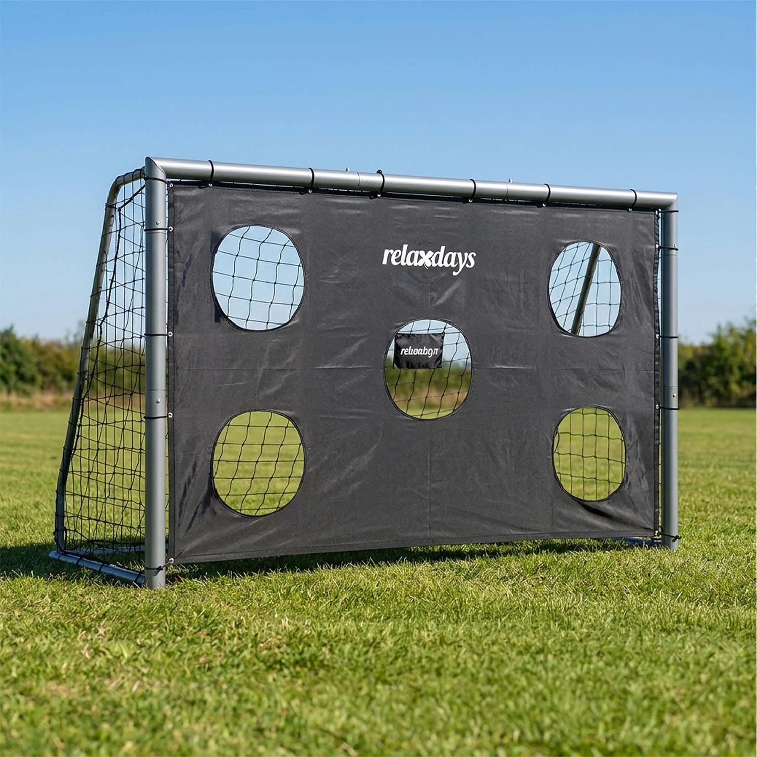Graues Stahl-Fußballtor mit schwarzer Torwand und 5 Ziellöchern auf grünem Rasen. Ideal für präzises Schusstraining.