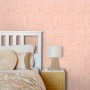Rosa Vliestapete mit modernem 3D-Muster an einer Schlafzimmerwand, neben weißem Bett und Nachttisch.