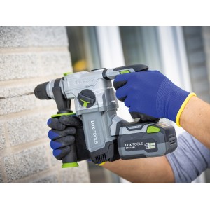 Mann bohrt mit LUX Akku-Bohrhammer, trägt blaue LUX Latex-Arbeitshandschuhe Gr. 10.