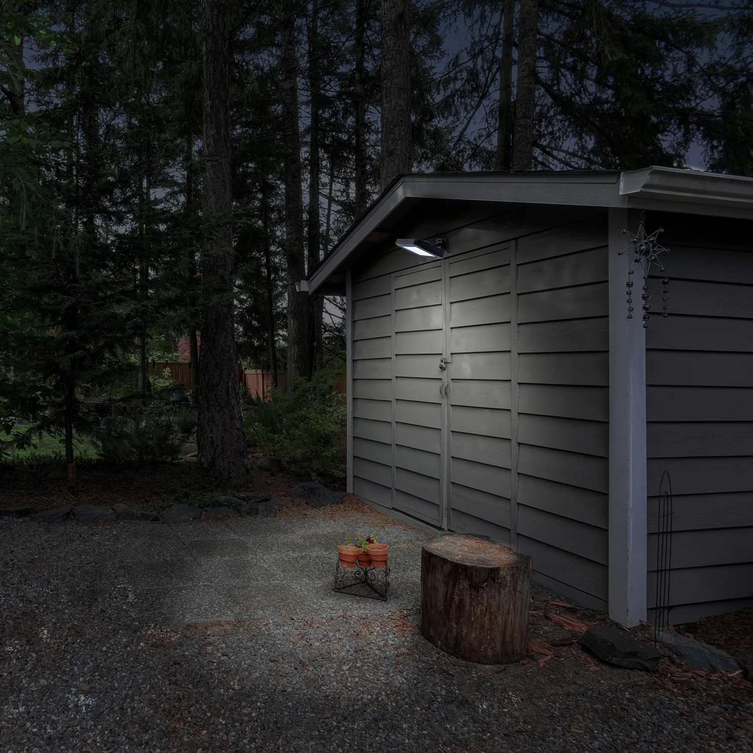 Schwarze LED Solar-Wandleuchte Pepe an einer Gartenhütte. Außenleuchte mit Bewegungsmelder.