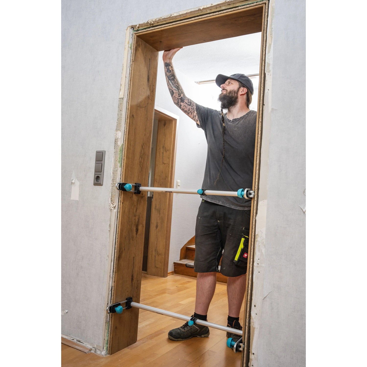 Mann installiert Holztürzarge mit zwei wolfcraft Türfutterstreben Easy. Die Spannwerkzeuge stabilisieren die Zarge beim Einbau.