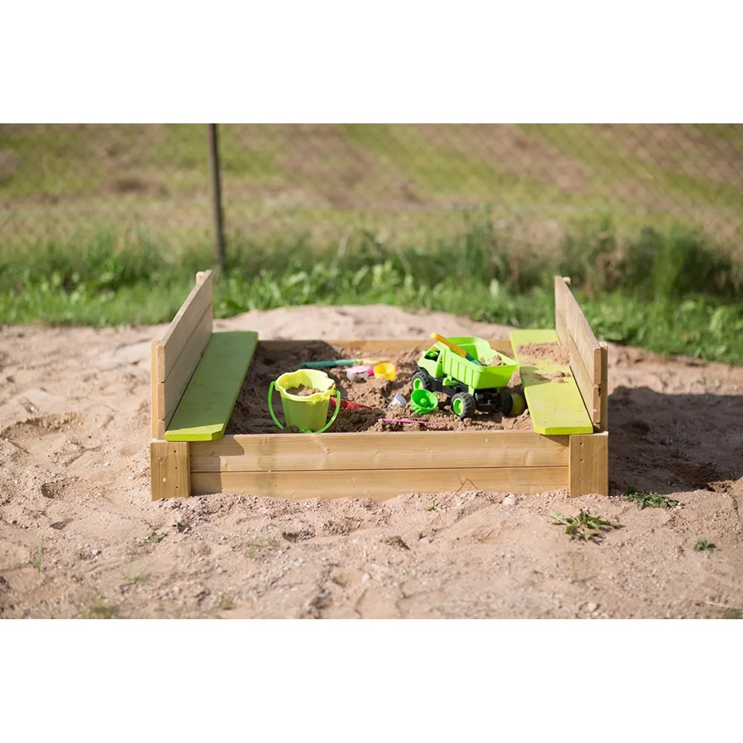 Wendi Toys Sandkasten mit Holzabdeckung und Sitzflächen, gefüllt mit Sand und Spielzeug.