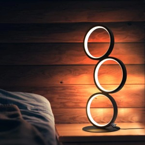 Schwarze NETTLIFE LED Tischlampe mit drei leuchtenden Ringen auf Nachttisch. Dimmbare Metall-Dekorleuchte für Innenräume.