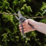 Hand schneidet Ast mit Kent & Stowe Gartenschere Bypass Traditionell. Präzise Gartenschere.