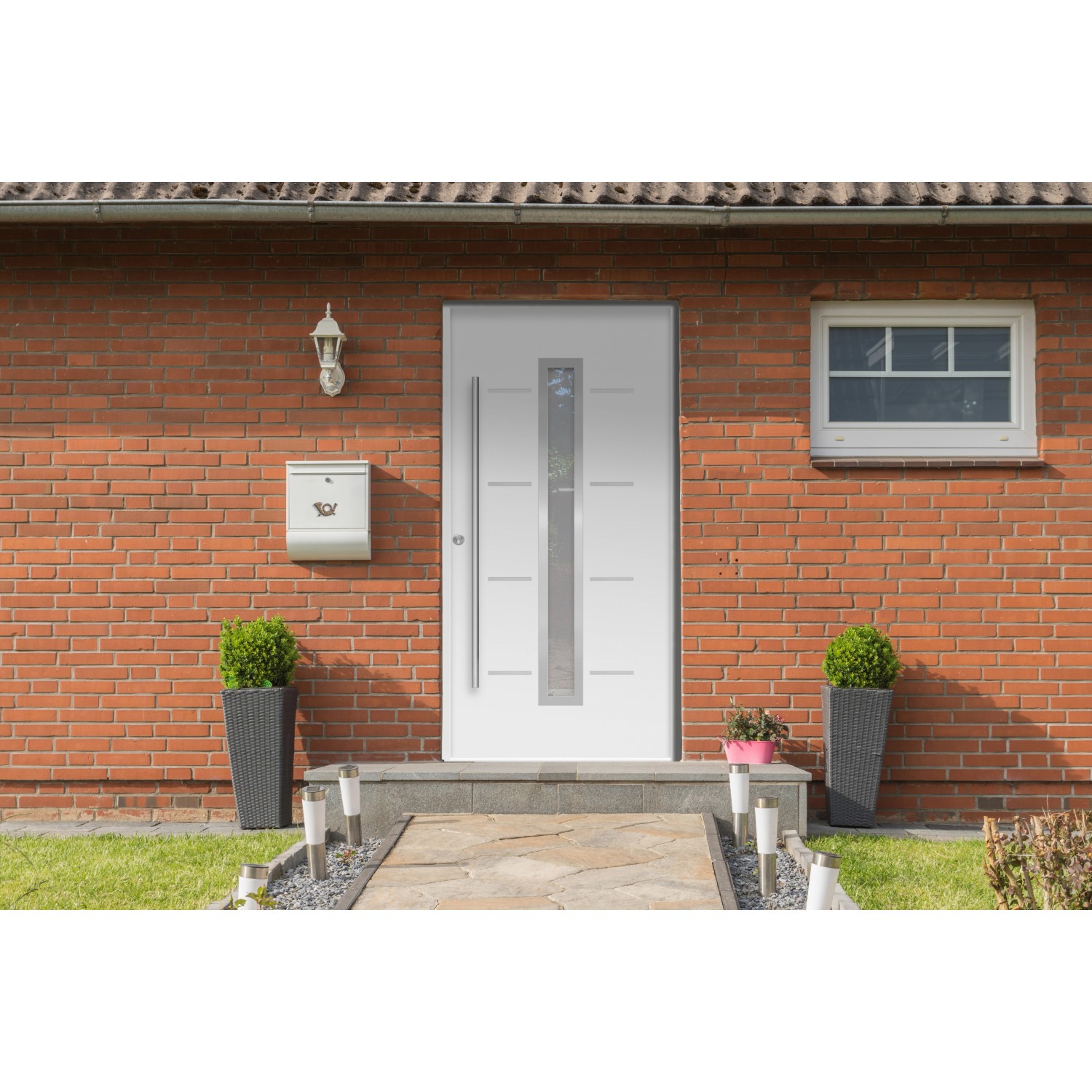 Weiße Haustür Thermospace Milano Prime mit Glasausschnitt und Edelstahlgriff vor Backsteinhaus.