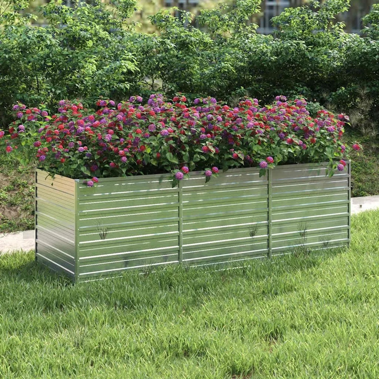 Silbernes furnicato Garten-Hochbeet aus verzinktem Stahl, bepflanzt mit bunten Blumen.