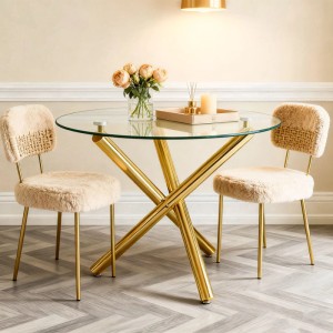 Runder Esstisch mit transparenter Glasplatte und goldenem Metall-Kreuzfußgestell im Wohnzimmer.