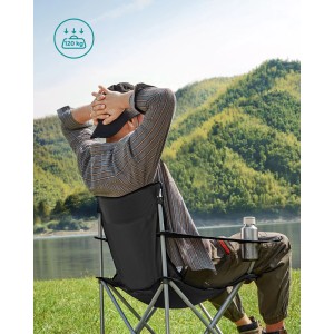 Schwarzes Songmics Campingstuhl-Set mit Getränkehalter, Person sitzt entspannt vor Berglandschaft.