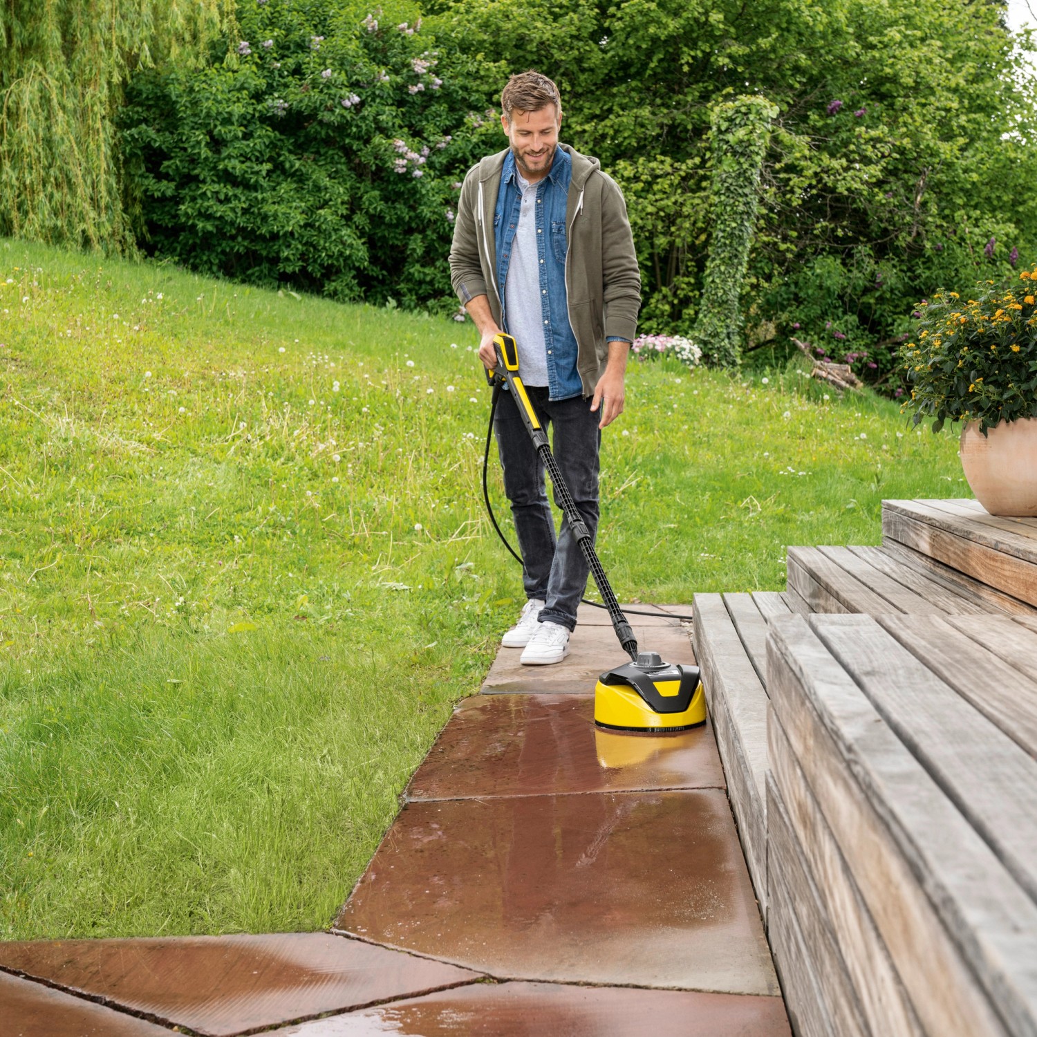 Mann reinigt Terrasse mit Kärcher Flächenreiniger T 5 T-Racer. Das Zubehör für Hochdruckreiniger sorgt für Sauberkeit.