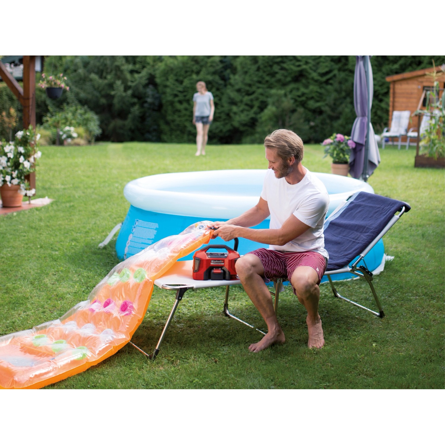 Einhell Hybrid-Kompressor Pressito beim Aufpumpen einer Luftmatratze im Garten.