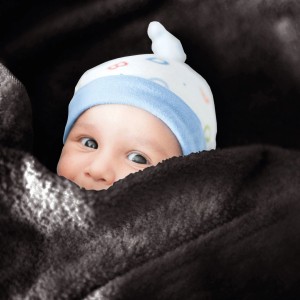 Baby unter Bestlivings Mikrofaser Babydecke in Schwarz (70x100 cm) mit Mütze.