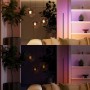 Wohnzimmer mit Philips Hue Wandschaltermodul. Zeigt dimmbare Leuchten: Oben helles, warmes Licht, unten gedimmtes, farbiges smartes Licht.
