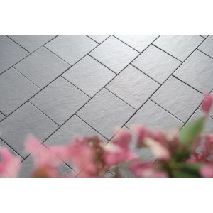 Diephaus Siva Terrassenplatten mittelgrau, Schieferoptik, diagonal verlegt auf Terrasse mit Blumen.