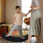 Kind balanciert auf schwarzem CCLIFE Holz Balance Board (85x30cm) mit Hilfe einer Erwachsenen. Montessori Spielzeug.