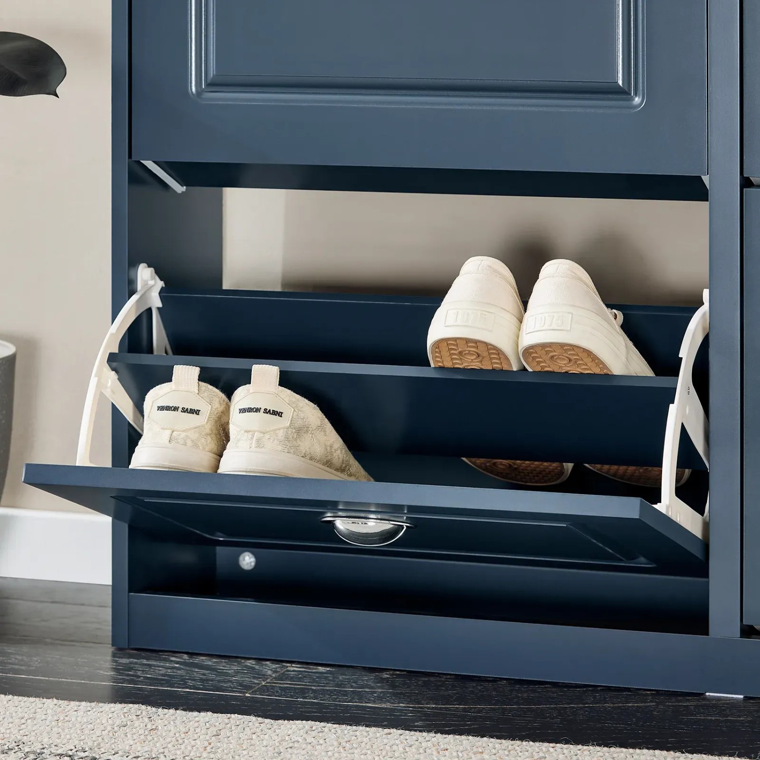 Dunkelblauer schmaler Schuhschrank mit 2 offenen Klappen, in denen Schuhe aufbewahrt werden.