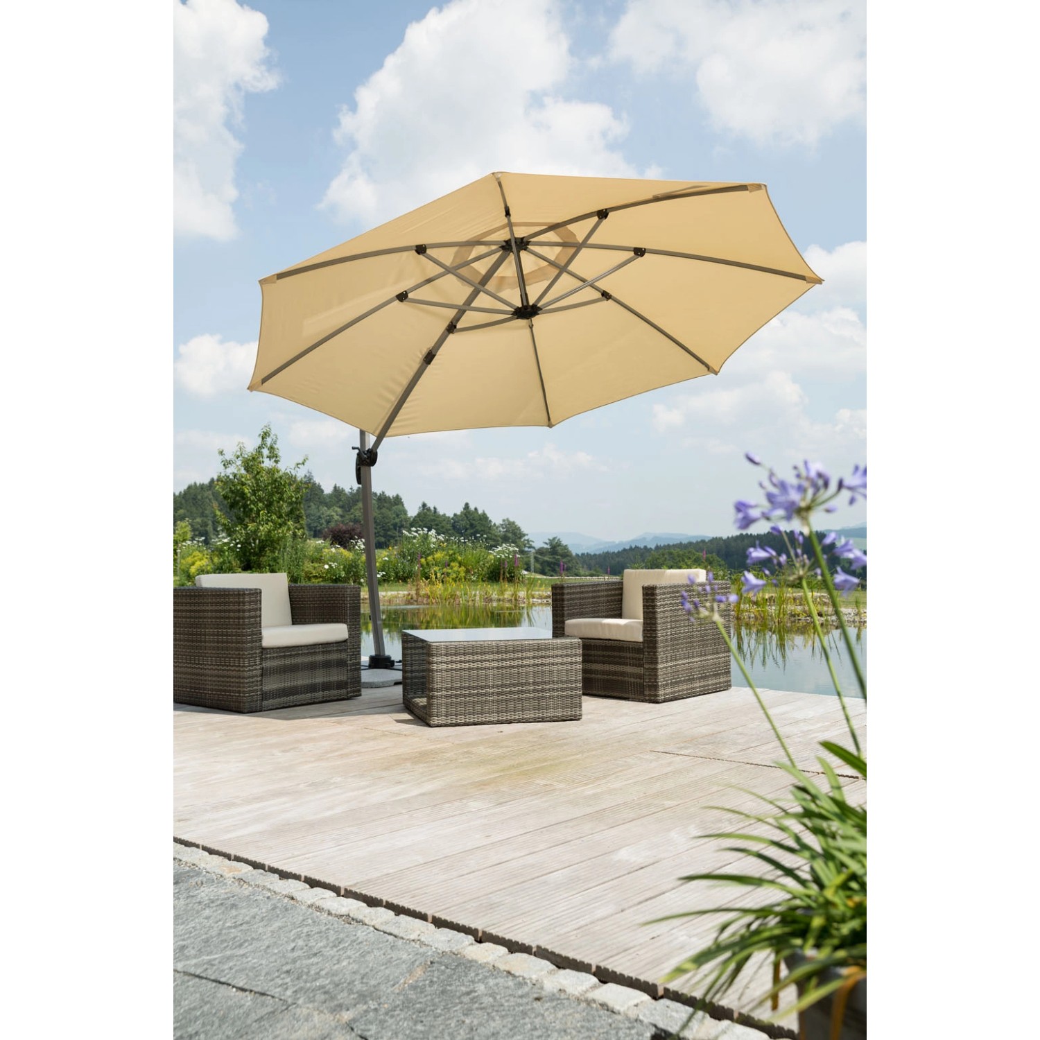 Sandfarbener Schneider Ampelschirm Rhodos Ø 350 cm mit Kurbel über Lounge-Set auf Holzterrasse.