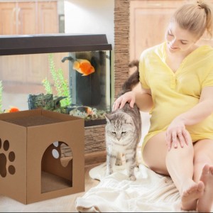 Braunes Katzenhaus aus Pappe mit Pfoten-Ausschnitten und Kratzbrett, eine Katze wird von einer Frau gestreichelt.