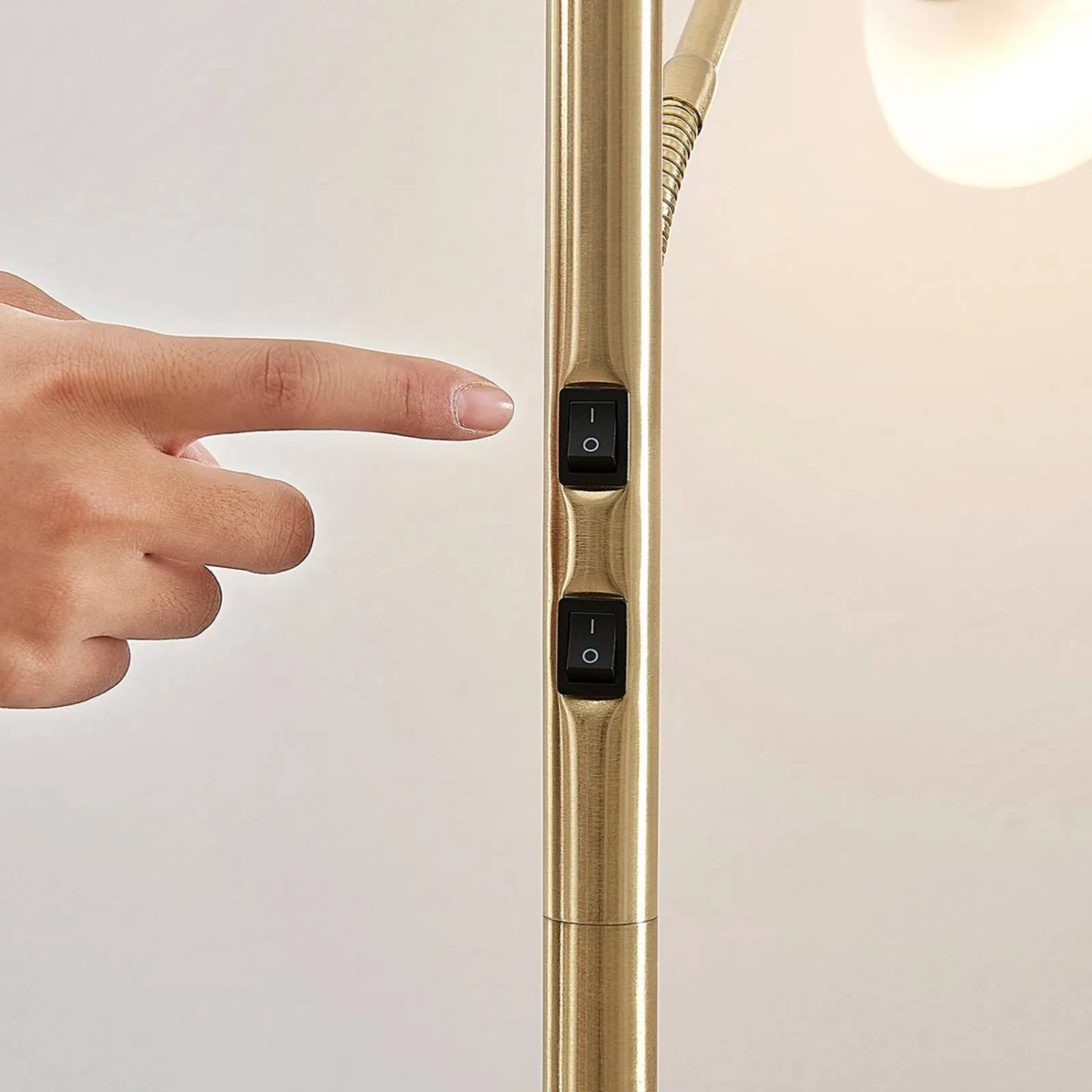 Hand betätigt Schalter an goldener Lindby Stehlampe Jost aus Metall. 2-flammige Wohnzimmerleuchte.