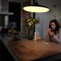 Frau mit Tasse unter Philips Hue Leuchte; Dimmschalter auf Küchentisch.