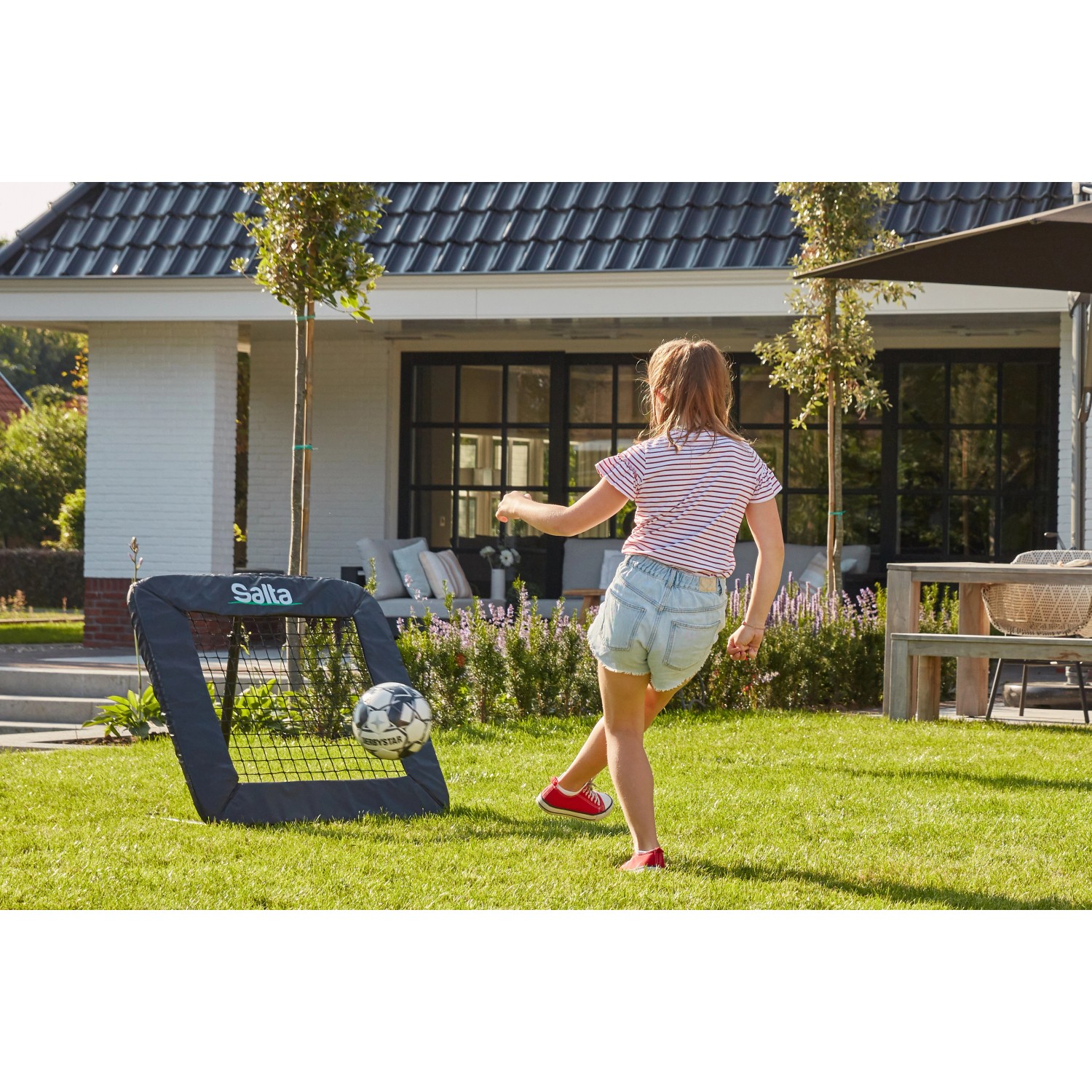 Salta Rückprallwand Motion: Mädchen spielt Fußball mit dem Rebounder im Garten.